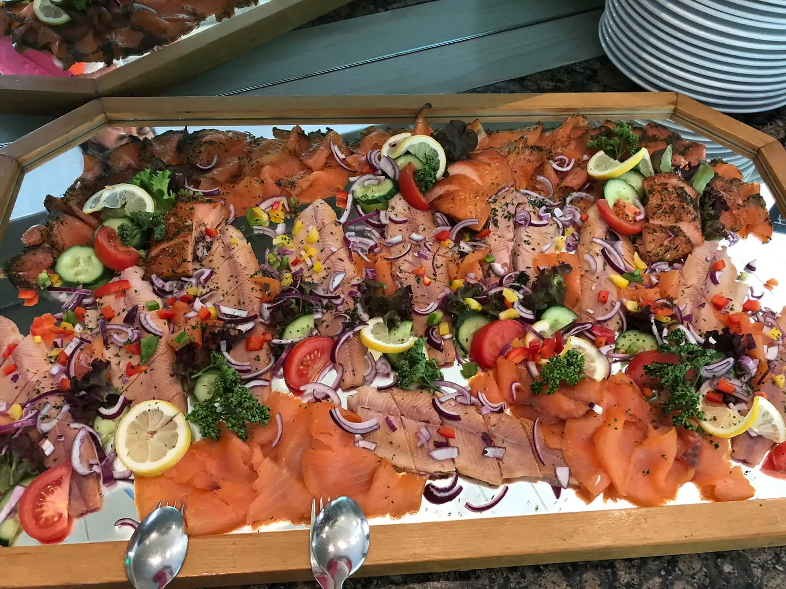 Platte mit Räucherlachs und Forellenfilets, bestreut mit roten Zwiebeln und Paprikawürfeln