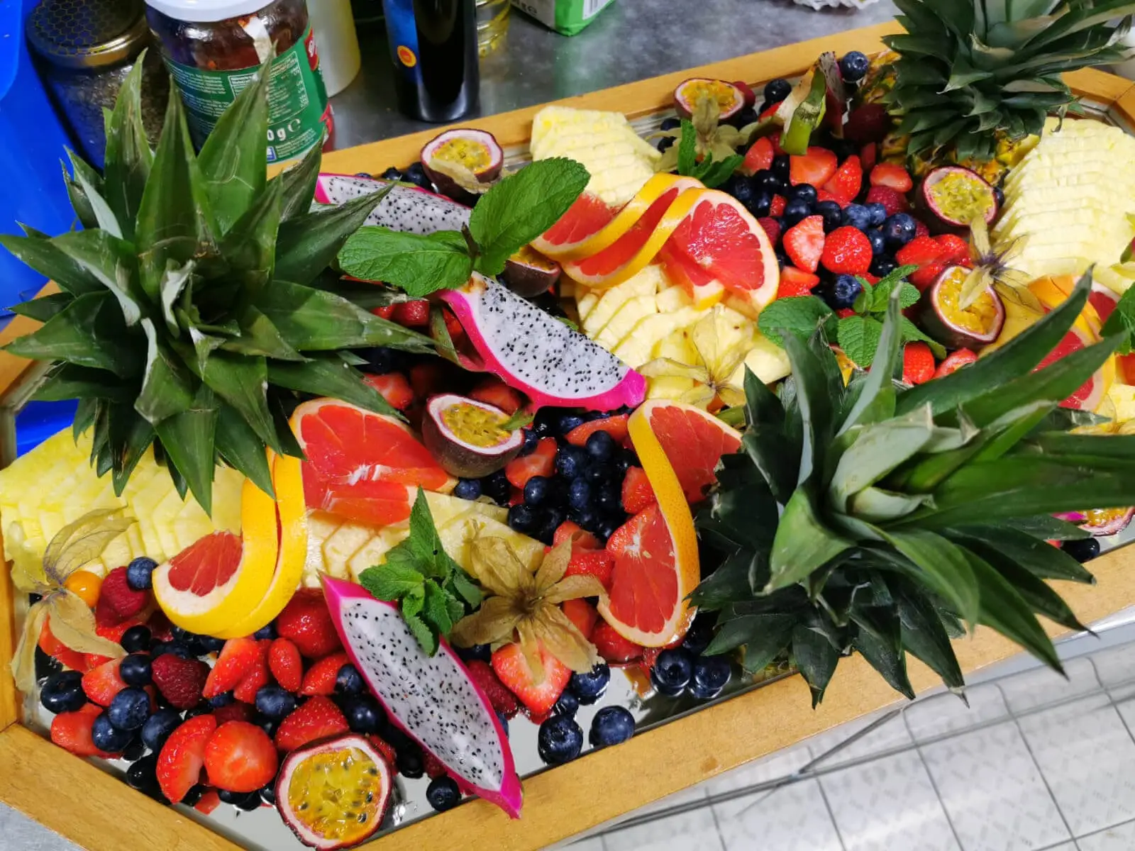 Große Obstplatte mit aufgeschnittener Ananas, Beeren und Maracuja in der Küche