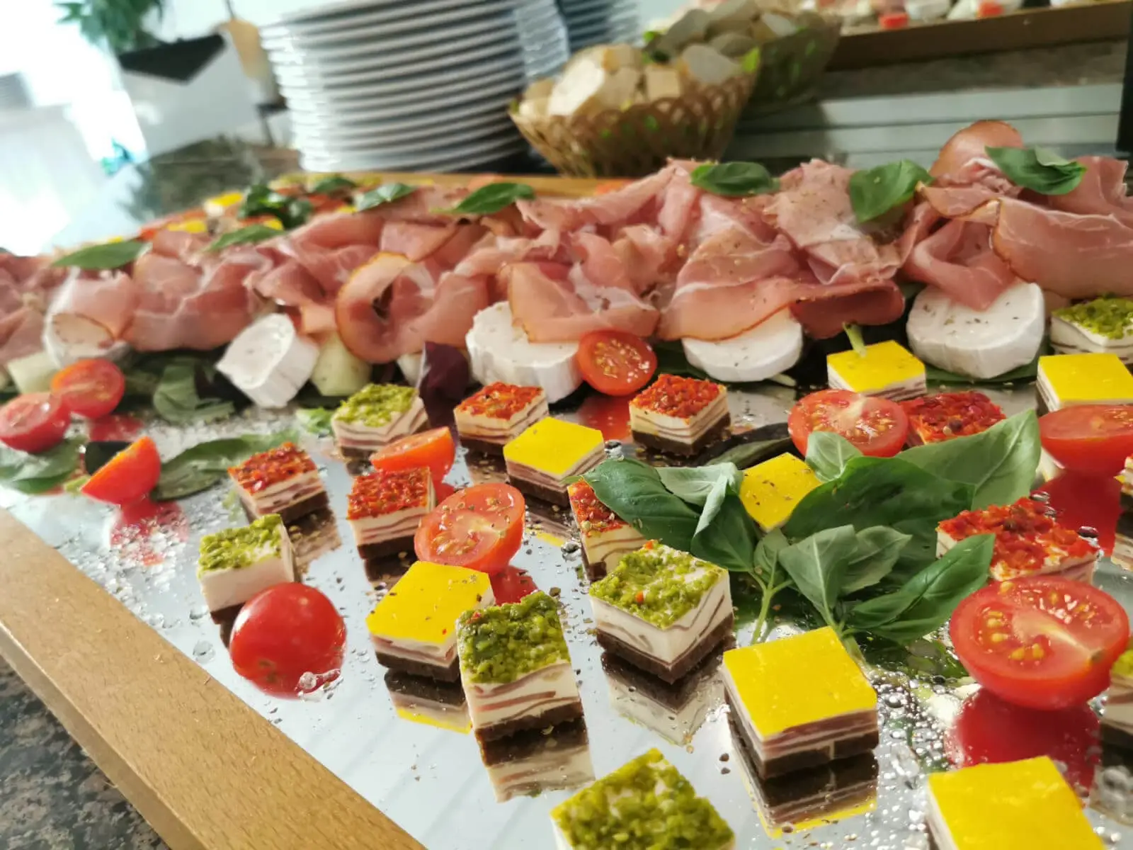 Schinkenplatte mit Ziegenkäse, davor Terrinenwürfel mit Pesto und Paprikahaube